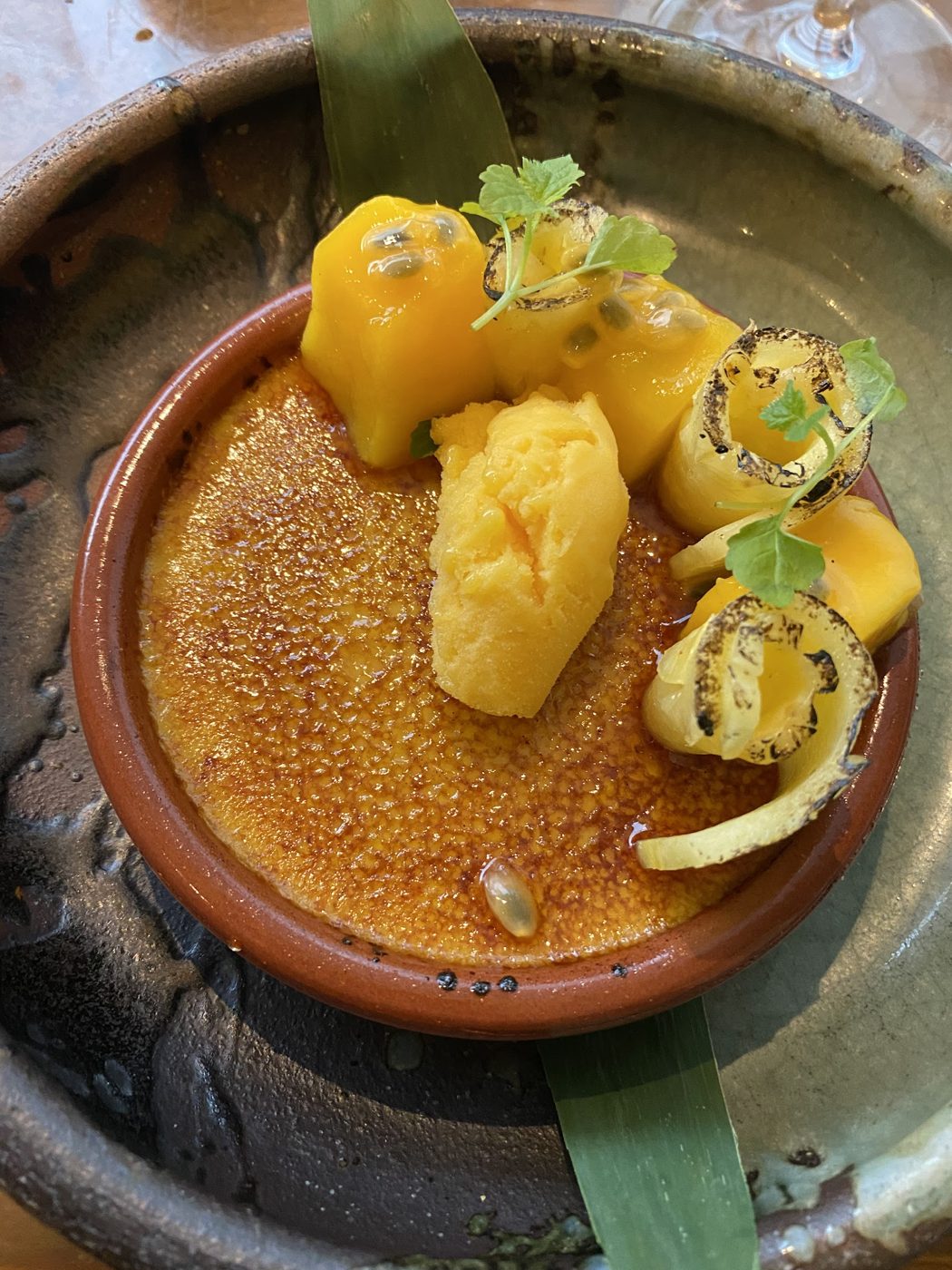 A golden-topped dish with mango cubes in a clay bowl