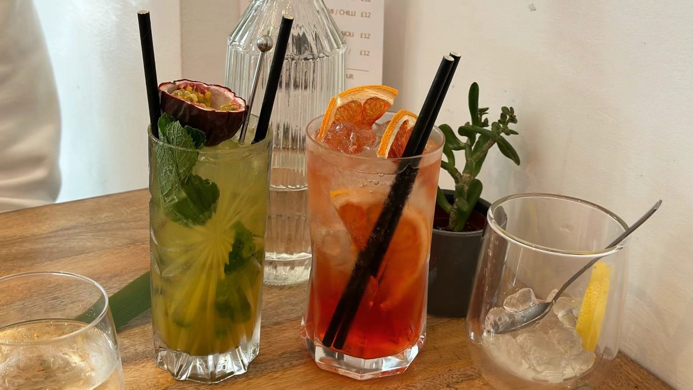 Two cocktails with straws, one with mint and lime, one with orange
