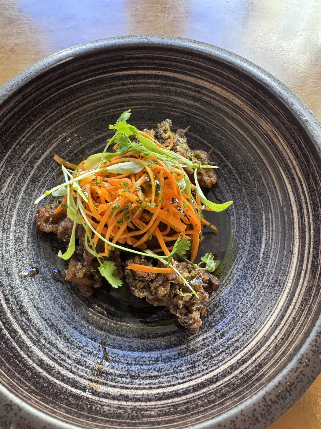 A crispy dish with shredded carrot and herbs