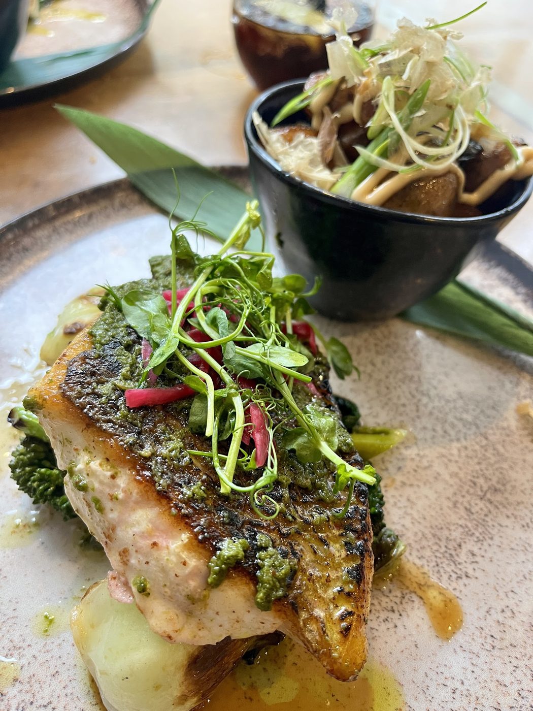 A crisp-skinned fish fillet topped with microgreens