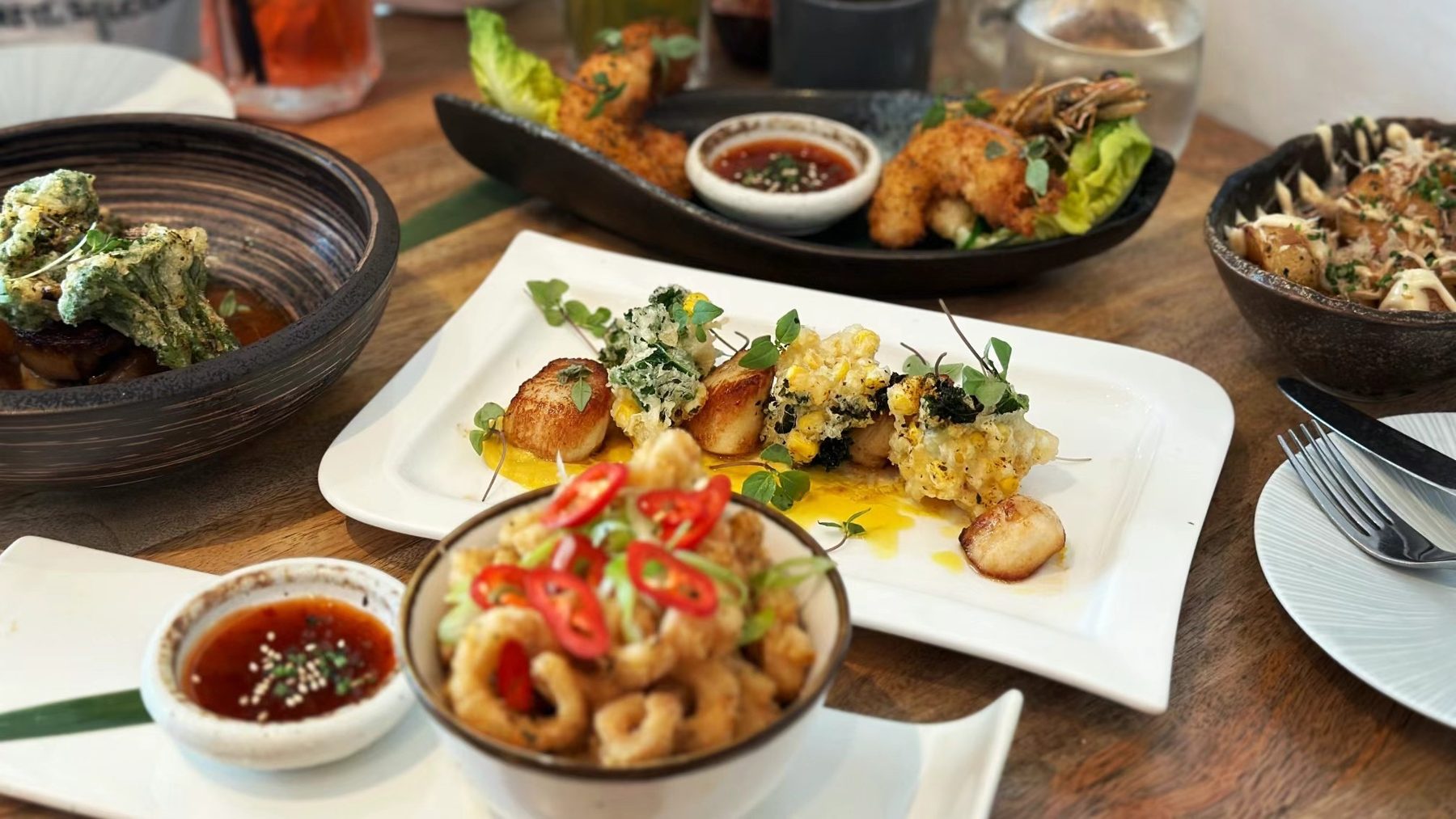 Several dishes on a wooden table with dipping sauces