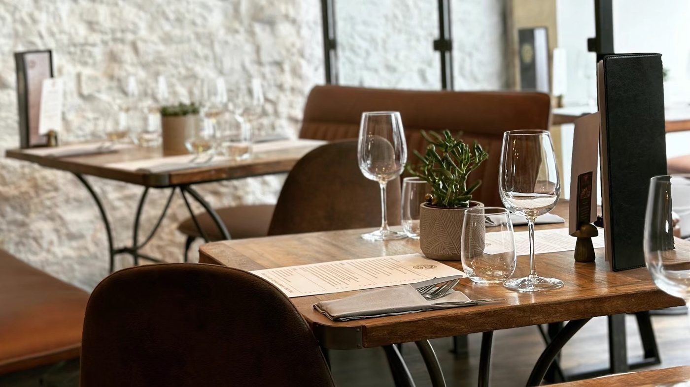 A table laid with wine glasses by a white brick wall